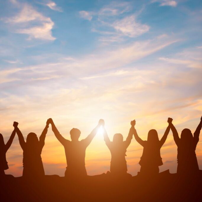 Silhouette of happy business team making high hands in sunset sky background for business teamwork concept Silhouette of happy business team making high hands in sunset sky background for business teamwork concept